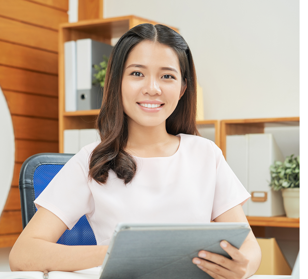 Professional woman smiling while using a tablet at her office desk
